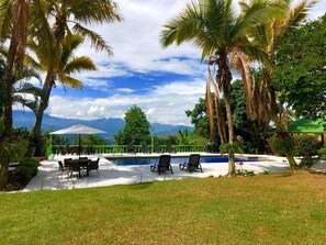 A pool area with lounge chairs and a view of mountains.