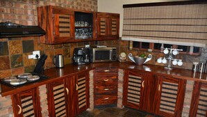 Een keuken met houten kastjes, een magnetron, een koffiezetapparaat en een waterkoker.