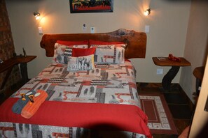 A bed with a patterned bedspread, a wooden headboard, and two bedside tables with lamps.