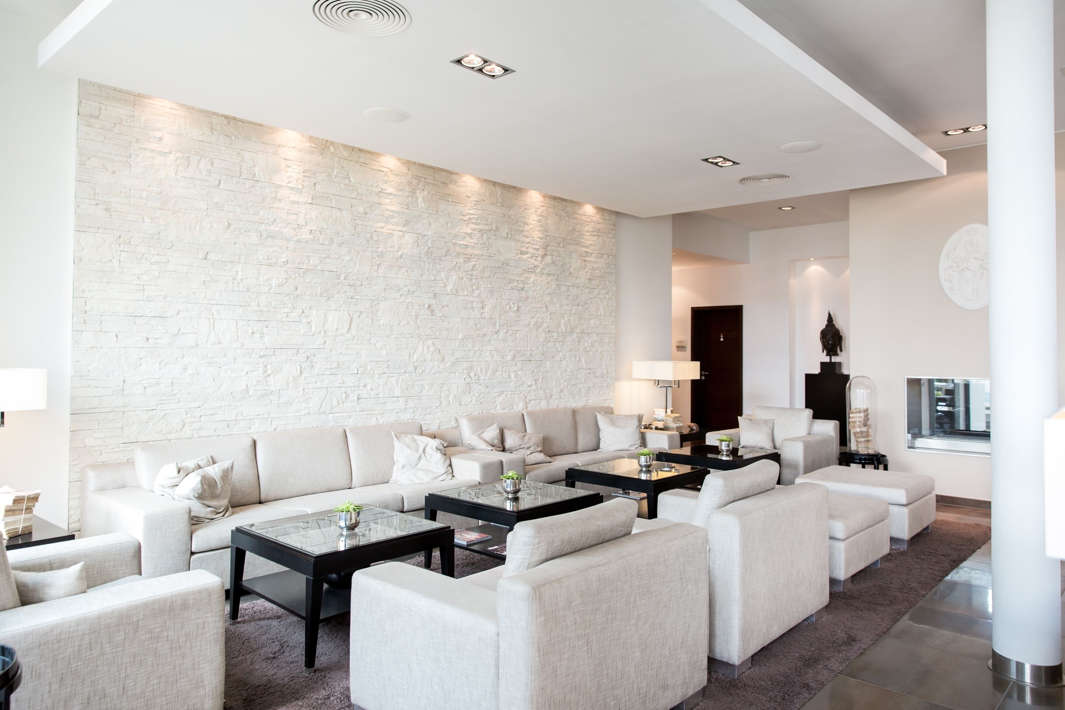 Una sala de estar moderna con una pared de ladrillo blanco, un sofá modular y una mesa de centro de vidrio.
