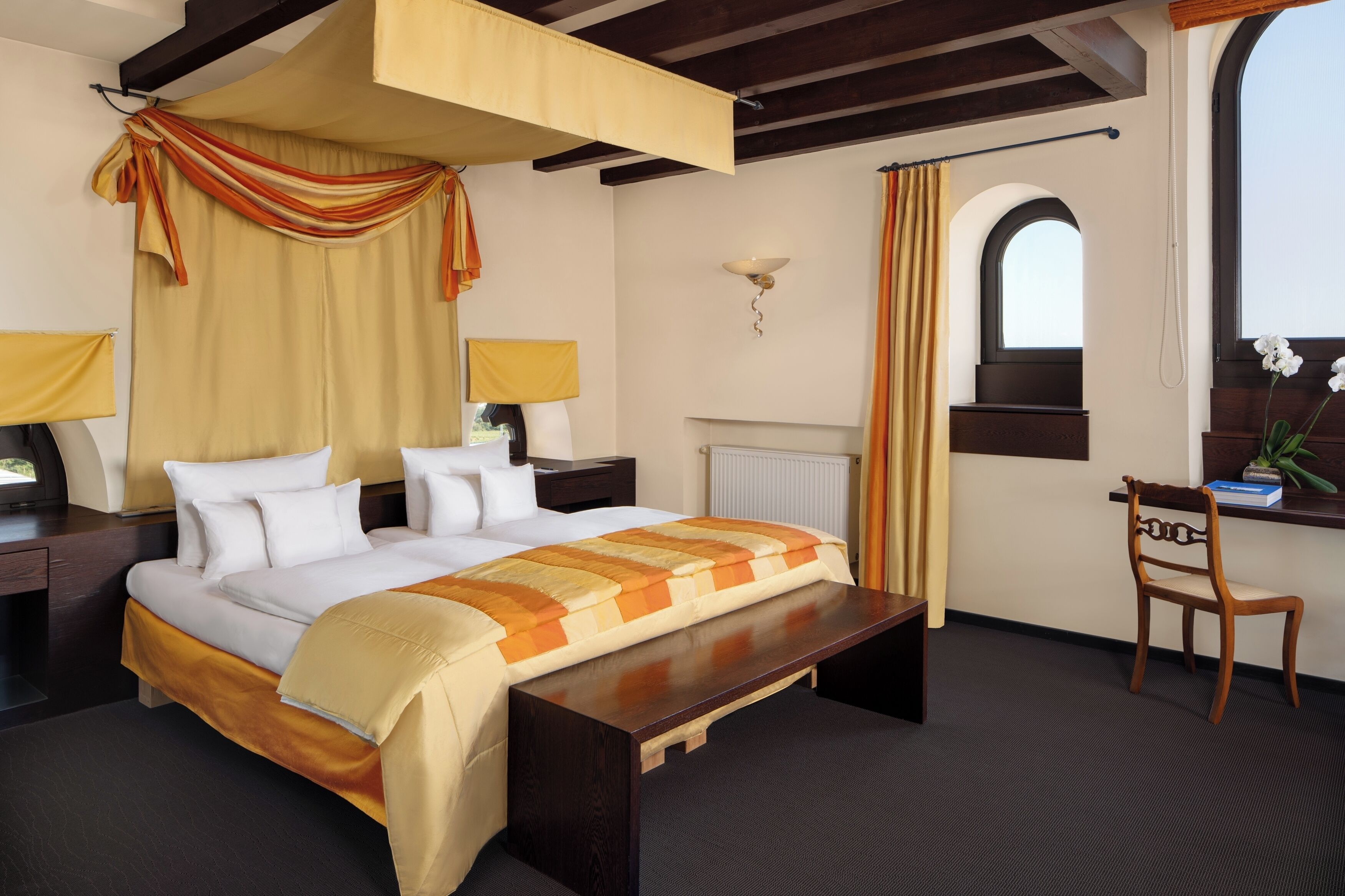 Een hotelkamer met een bed, een bureau, een stoel, een raam en een lamp.