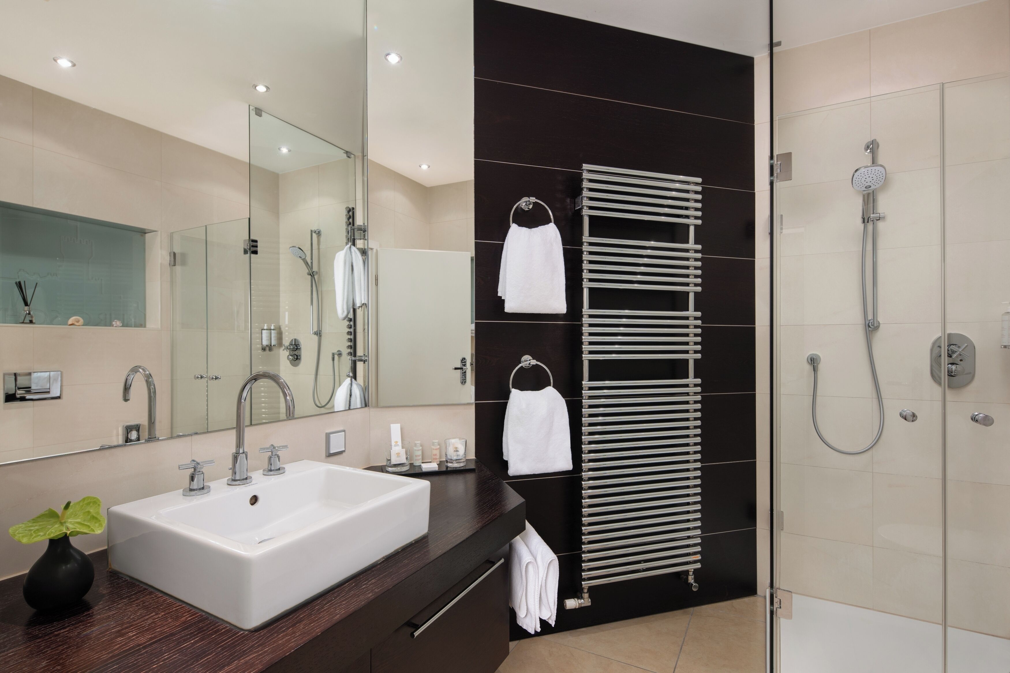 Un baño moderno con un lavamanos grande, un espejo, un perchero para toallas y una ducha con mampara de vidrio.