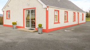 A single-story house with a gabled roof, a front door, and two windows on the side. - Ellen's Cottage (Mountcharles)