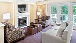 A living room with patterned sofas, a fireplace, a television, and a balcony with outdoor furniture.