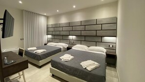 A modern hotel room with two beds, a desk, and a flat-screen TV. - B&B Bertani (Modena)