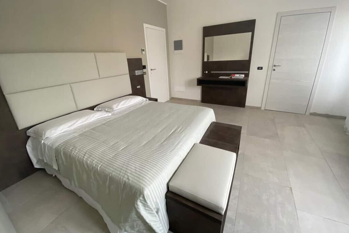 Une chambre moderne avec un grand lit, une table de chevet, un miroir et une armoire.