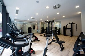 A modern gym with cardio machines, weightlifting equipment, and mirrors on the walls.