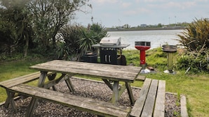 A picnic table with a grill and a bird feeder by a lake. - Cairbre House (Dungarvan)