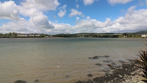 A coastal landscape with a body of water, distant buildings, and a clear sky. - Cairbre House (Dungarvan)