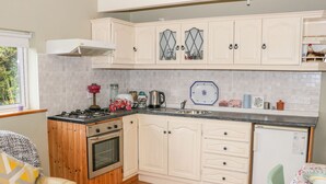 Una cocina compacta con armarios de madera, una estufa a gas, horno integrado y un refrigerador pequeño.