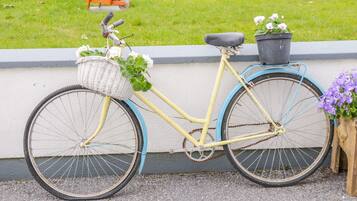 A yellow bicycle with a basket and a potted plant attached to the rear.