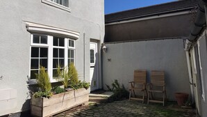 A building with a white exterior, a wooden bench, and a potted plant. - Witts End (Redcar)