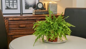 A round table with a potted fern, a clock, and books on a wooden desk. - Witts End (Redcar)