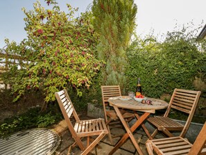 A round wooden table with four chairs, a bottle of champagne, and a bowl of fruit. - Swallows Loft (Kingsbridge)