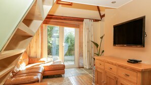 A modern living room with a sofa, wooden cabinet, and a television. - Swallows Loft (Kingsbridge)