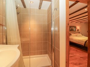 A bathroom with a glass shower enclosure, a white sink, and a wooden ceiling. - Swallows Loft (Kingsbridge)