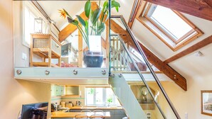 A modern kitchen with a dining area, a staircase, and a large window. - Swallows Loft (Kingsbridge)