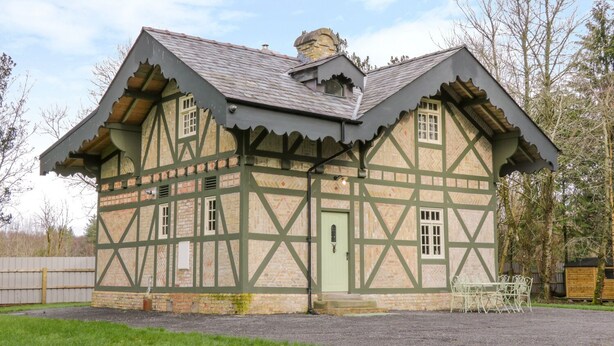Ein traditionelles Gebäude im Tudor-Stil mit einem steilen Dach, freiliegenden Fachwerkkonstruktionen und einem kleinen Vorbereich.