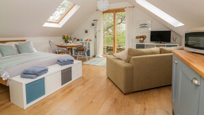 Un dormitorio estilo loft acogedor con cama, sofá, televisor y zona de comedor.