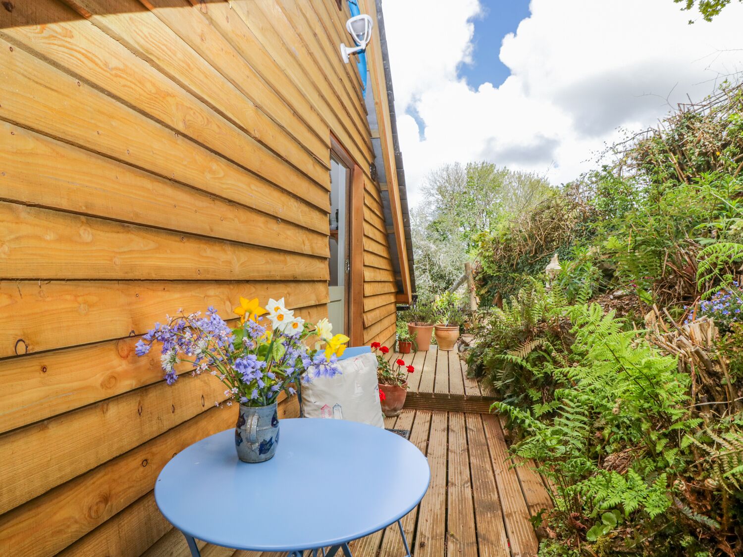 A wooden cabin with a blue table and a vase of flowers.
