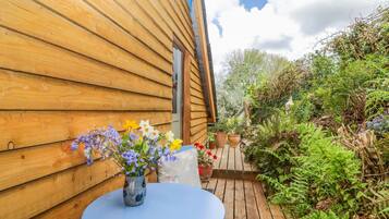 A wooden cabin with a blue table and a vase of flowers.