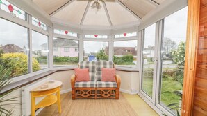 A conservatory with a sofa, a small table, and a ceiling fan. - Dune Haven (Truro)