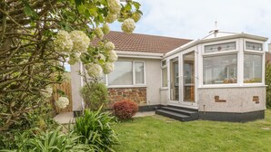 A house with a stone facade, a tiled roof, and a bay window. - Dune Haven (Truro)