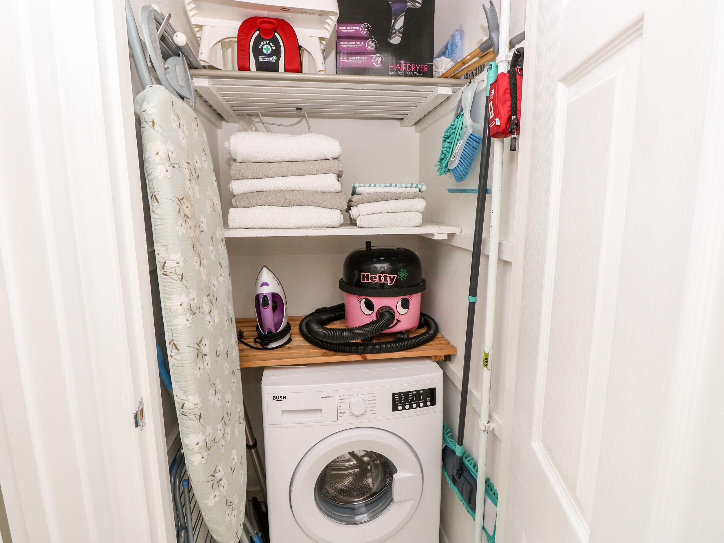 Un espace dédié à la lessive, équipé d’un lave-linge, d’un fer à repasser et d’un aspirateur.