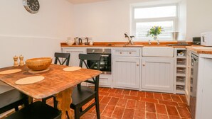 A compact kitchen with white cabinets, a wooden dining table, and a window with a view. - 11 Tower Street (Richmond)