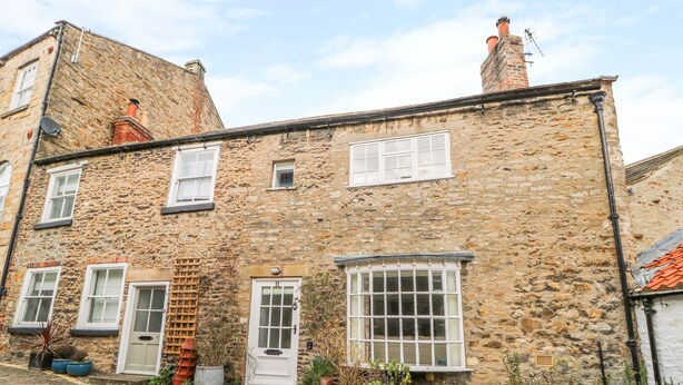 A stone building with multiple windows and doors, a cobblestone street, and potted plants. - 11 Tower Street (Richmond)