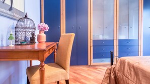 A bedroom with a wooden desk, a chair, a bed with a beige cover, and a wardrobe with blue doors. - JOIVY Cozy Flat for 4 w/ Patio, Nearby Navigli (Milan)
