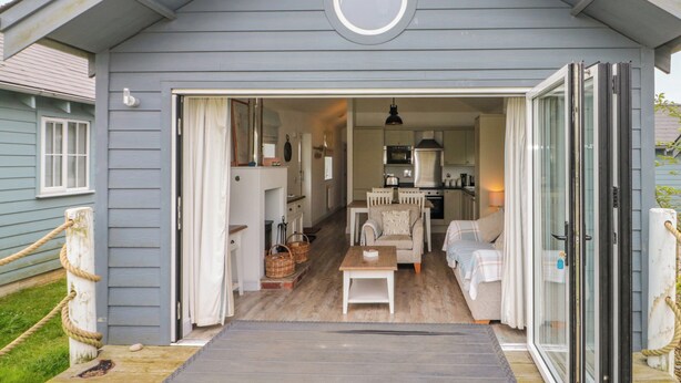 A cozy cottage with a wooden deck, a dining area with a table and chairs, and a kitchen with modern appliances. - Sea Breeze (Filey)