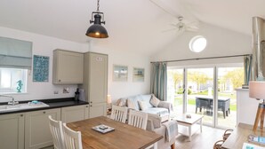 A cozy kitchen with a dining area, a ceiling fan, and a view of the garden through large glass doors. - Sea Breeze (Filey)