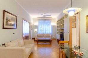 A living room with a sofa, a coffee table, a TV, and a bookshelf. - JOIVY Lovely Apt with Communal Pool in Nervi (Genoa)