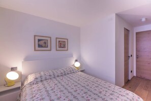 Une chambre à coucher avec un lit, deux lampes de chevet et deux tableaux encadrés accrochés au mur.
