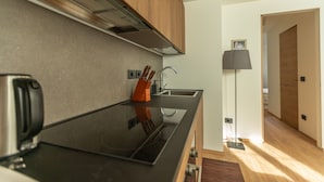 A modern kitchen with a black countertop, stainless steel appliances, wooden cabinets, and a built-in sink.