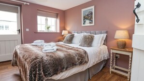 Un dormitorio con una cama, dos mesitas de noche, una ventana y un cuadro en la pared.