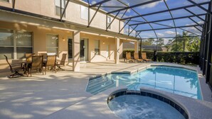 Un área de piscina exterior cubierta con sillones de descanso y una bañera de hidromasaje.