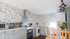 Een kleine keuken met een magnetron, broodrooster, spoelbak, kookplaat en wasmachine.