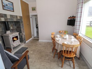 Una sala de estar acogedora con chimenea, una mesa de comedor preparada para cuatro personas y un sofá confortable.