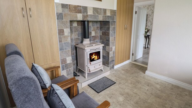 Un salón acogedor con chimenea de piedra, sofá gris y aparador de madera.