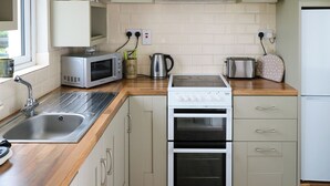 Una cocina moderna con un lavamanos de acero inoxidable, microondas, hervidor, tostadora y horno empotrado.