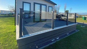 Ein modernes, mobilheimartiges Haus mit flachem Dach, großen Fenstern und einer überdachten Terrasse.