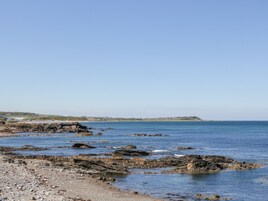 A rocky shoreline with calm water and a clear sky.