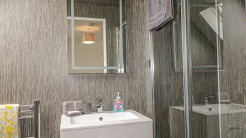 A modern bathroom with a large mirror, a sink, and a glass shower enclosure.