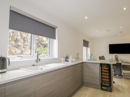 A modern kitchen with a large window, a built-in wine cooler, and a flat-screen TV mounted on the wall.