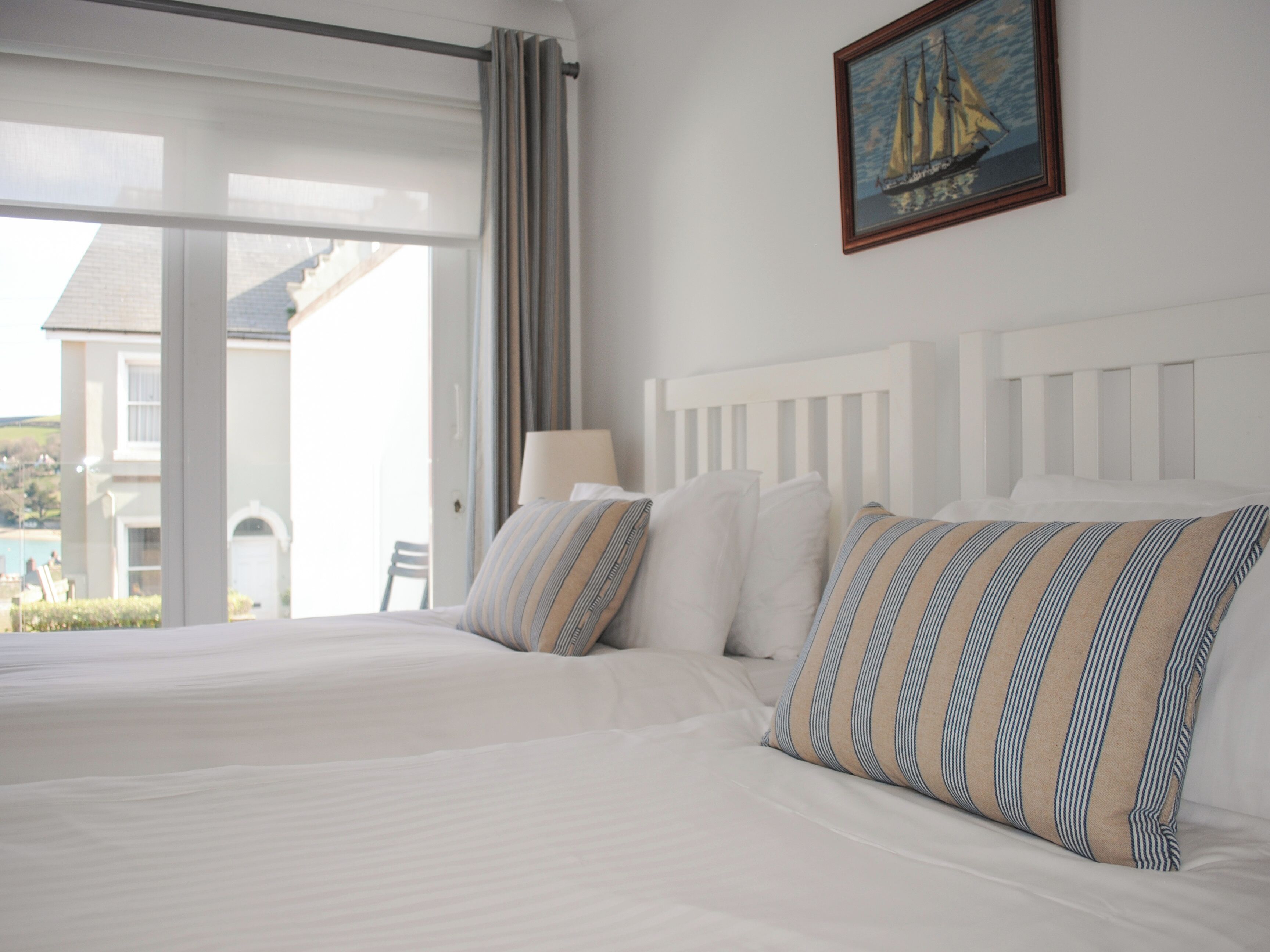 Quarto de hotel com uma cama grande, uma janela com cortinas e um quadro na parede.