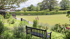 Un parc avec une pelouse, des bancs et une grande variété de plantes.