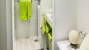 A modern bathroom with a glass shower enclosure, white tiles, and a green towel. - San Marino 2 (Los Cristianos)