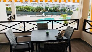 A balcony with a table and chairs, overlooking a swimming pool and buildings. - San Marino 2 (Los Cristianos)